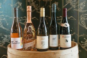 Five wine bottles on a white barrel.