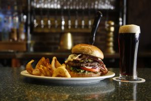 A photograph featuring a burger and beer on a counter.