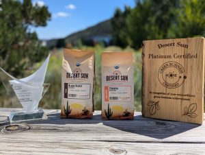 Photograph of two bags of coffee beans and two awards on top of a wooden ledge.